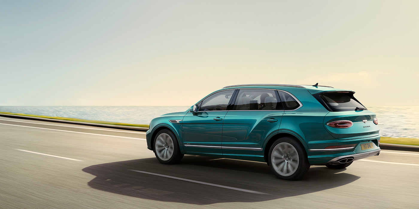 Bentley Seoul Rear view of a Topaz blue Bentley Bentayga EWB Azure, cruising along a sea side road.