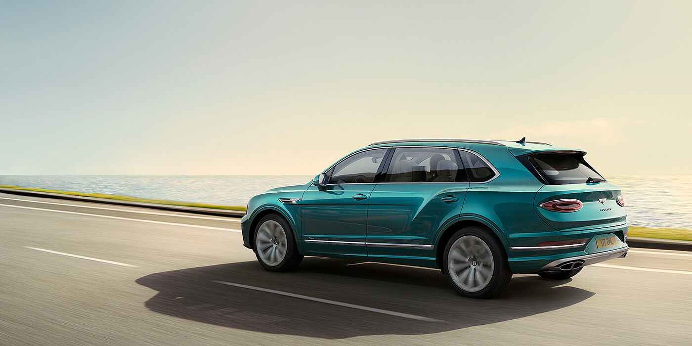 Bentley Seoul Rear view of a Topaz blue Bentley Bentayga EWB Azure, cruising along a sea side road.